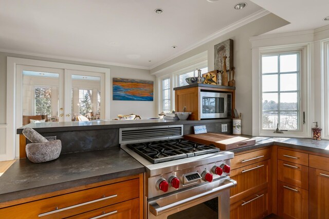 kitchen with french doors, crown molding, high end stainless steel range, dark countertops, and brown cabinetry