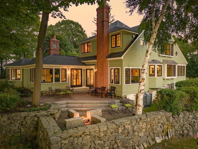 back of house with french doors, a chimney, a shingled roof, a patio area, and a fire pit