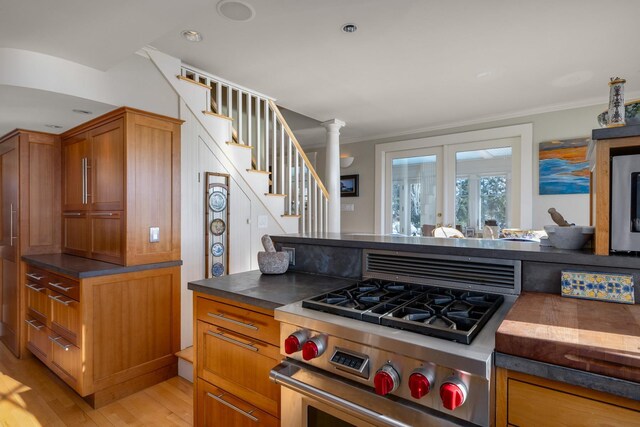 kitchen with crown molding, stainless steel range, dark countertops, and light wood-style floors