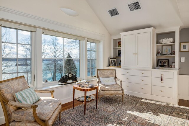 living area featuring vaulted ceiling, wood finished floors, visible vents, and built in features