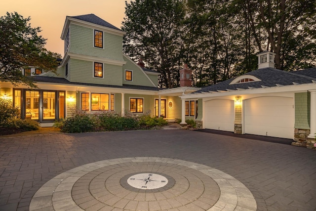 view of front of home featuring stone siding, decorative driveway, a shingled roof, and an attached garage