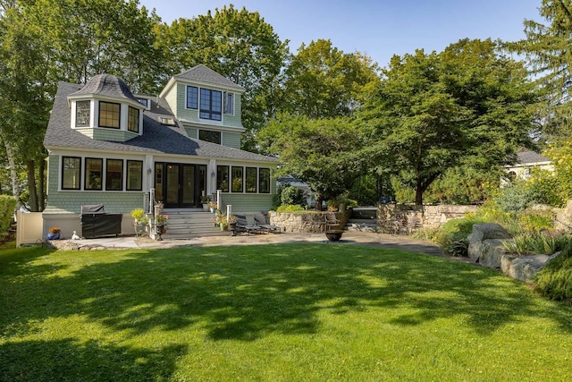 back of property featuring entry steps, a patio area, a shingled roof, and a lawn