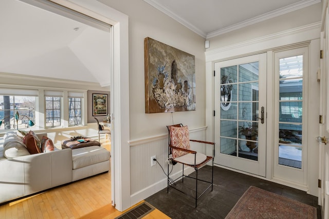 doorway featuring a healthy amount of sunlight, a wainscoted wall, crown molding, and visible vents