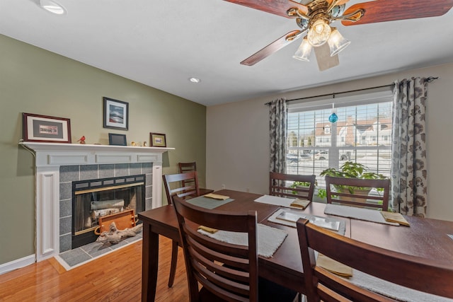 dining room featuring recessed lighting, a ceiling fan, wood finished floors, a tile fireplace, and baseboards