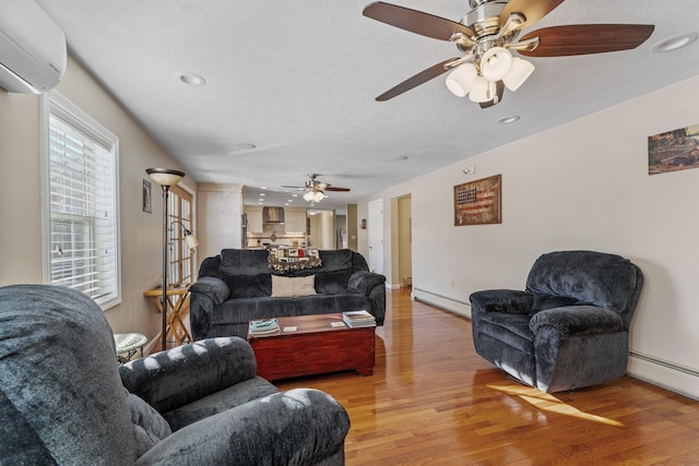 living room featuring light wood finished floors, baseboard heating, a wall mounted AC, a baseboard heating unit, and baseboards