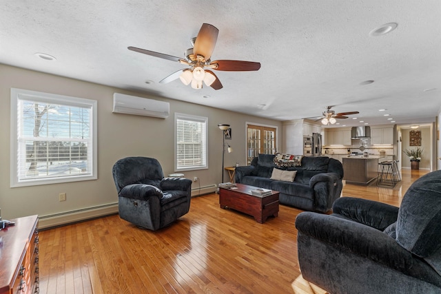 living area featuring plenty of natural light, light wood-style flooring, a baseboard heating unit, and a wall mounted air conditioner