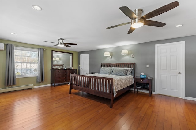 bedroom with a wall unit AC, hardwood / wood-style flooring, recessed lighting, baseboards, and baseboard heating