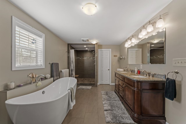 full bathroom with a stall shower, a sink, radiator heating unit, and double vanity