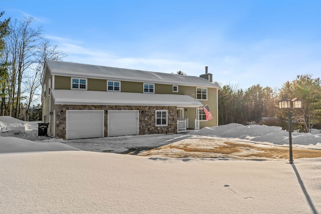 view of front facade featuring an attached garage, stone siding, and aphalt driveway