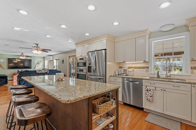 kitchen with tasteful backsplash, a kitchen island, light stone countertops, stainless steel appliances, and a sink