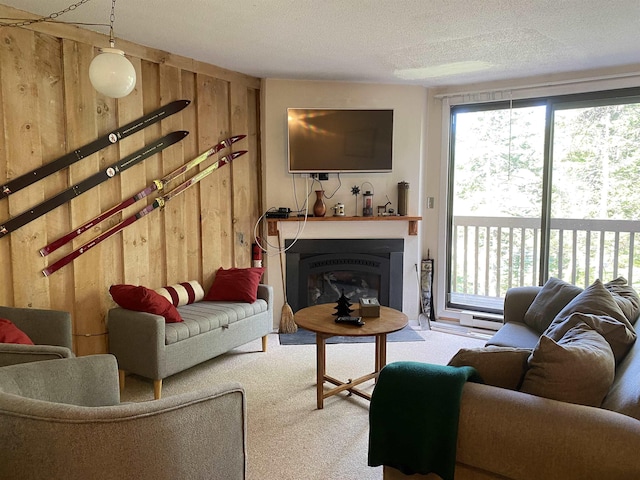 living room with a glass covered fireplace, carpet flooring, wooden walls, and a textured ceiling