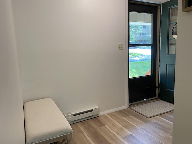 doorway to outside featuring a baseboard radiator, baseboards, and wood finished floors