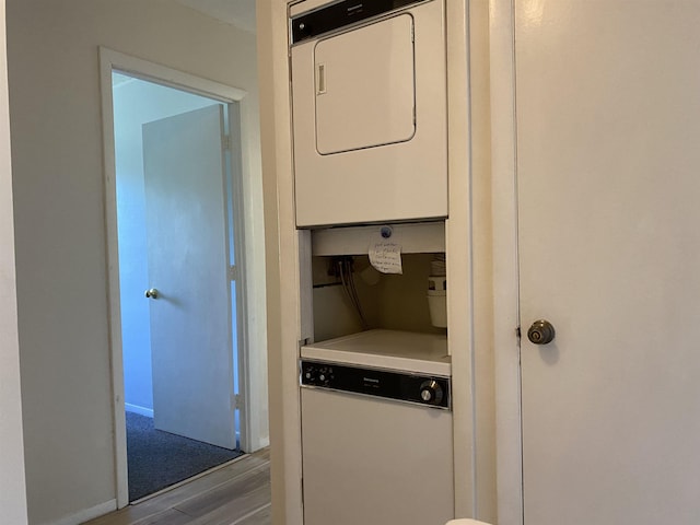 laundry room featuring laundry area, stacked washing maching and dryer, and wood finished floors