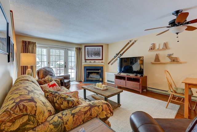 living room with a textured ceiling, a fireplace with flush hearth, and wood finished floors