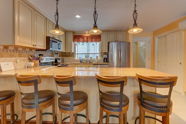 kitchen with stainless steel appliances, pendant lighting, a peninsula, and tasteful backsplash