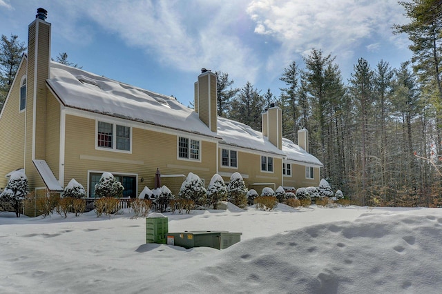 snow covered back of property with a chimney