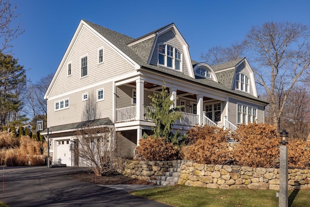 view of front of property with a porch, aphalt driveway, a garage, a gambrel roof, and roof with shingles