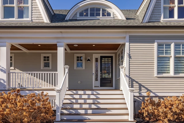 doorway to property with a shingled roof and a porch