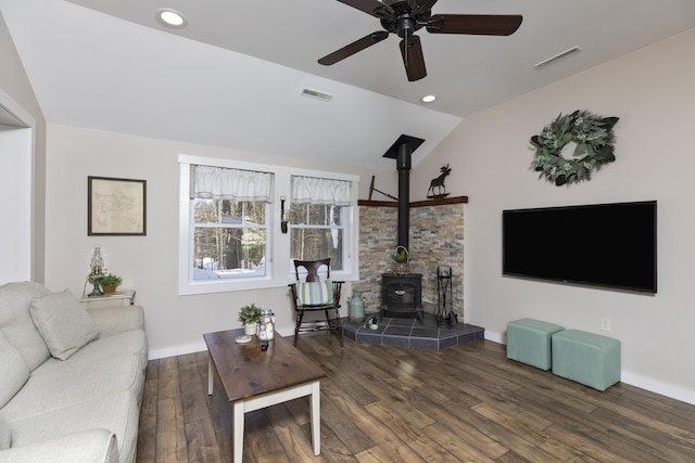 living room featuring a wood stove, visible vents, wood finished floors, and lofted ceiling