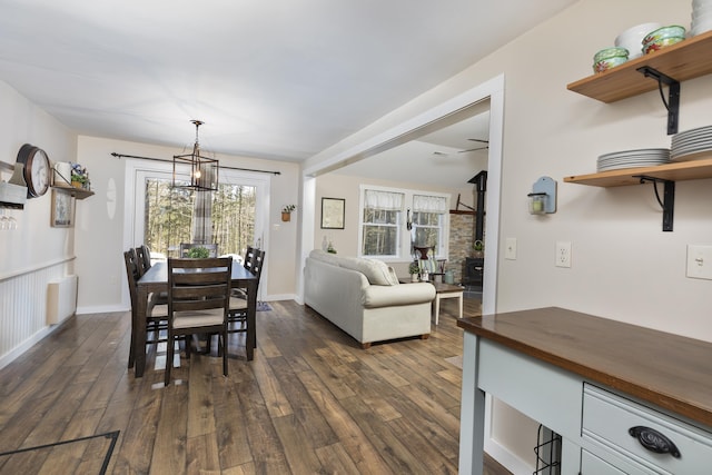 dining space with baseboards, dark wood finished floors, and a notable chandelier