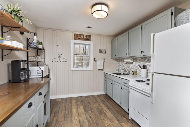 kitchen featuring dark wood-style flooring, butcher block counters, decorative backsplash, a sink, and white appliances