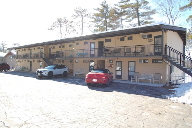 view of building exterior with stairs and uncovered parking