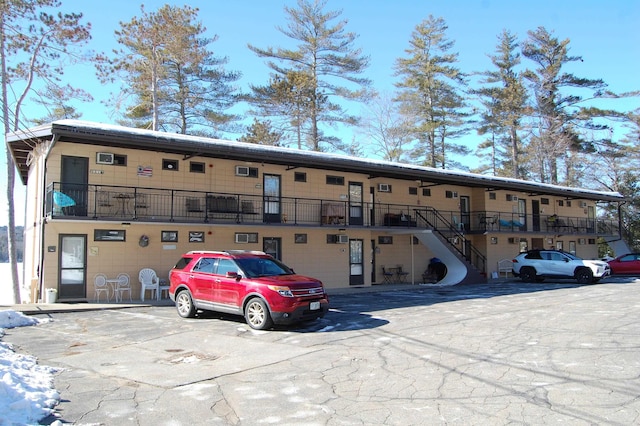 view of building exterior with uncovered parking and stairs