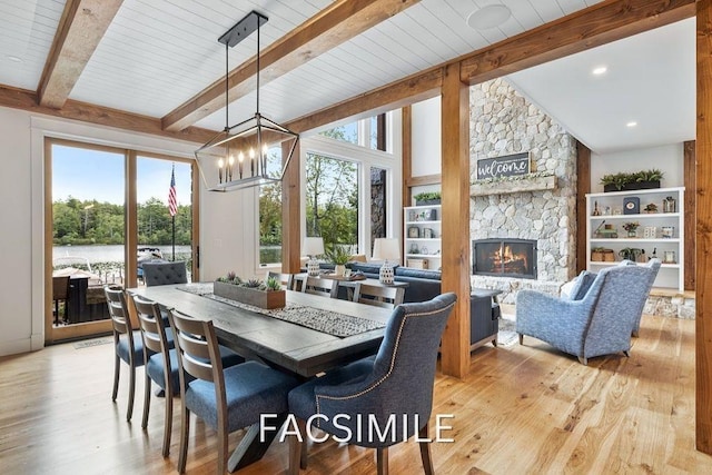 dining space featuring vaulted ceiling with beams, light wood-style flooring, a fireplace, and a wealth of natural light