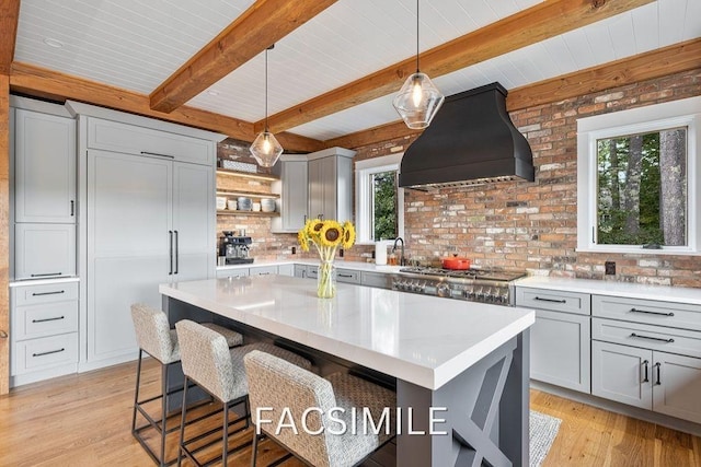 kitchen featuring a wealth of natural light, gray cabinetry, and custom exhaust hood