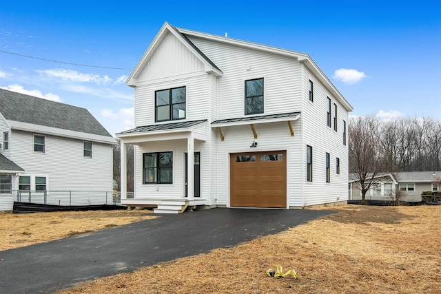 modern inspired farmhouse with metal roof, aphalt driveway, an attached garage, board and batten siding, and a standing seam roof