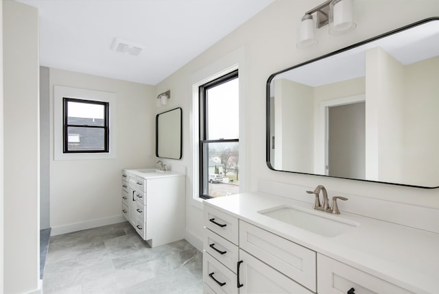 full bath with plenty of natural light, two vanities, and a sink