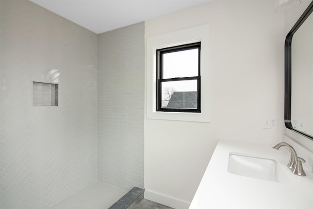 full bathroom with baseboards, a sink, and tiled shower