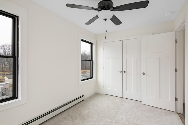 unfurnished bedroom with a baseboard heating unit, a closet, light carpet, and ceiling fan