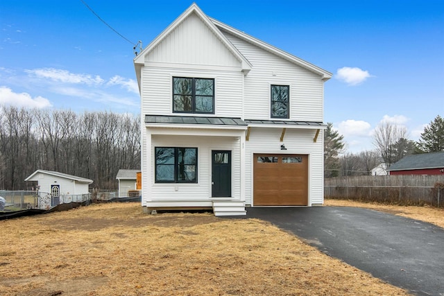 modern inspired farmhouse with a garage, a standing seam roof, fence, and aphalt driveway