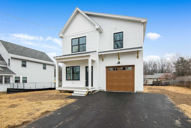 modern farmhouse style home featuring aphalt driveway, board and batten siding, and an attached garage