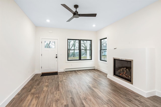 foyer featuring baseboards, a glass covered fireplace, a baseboard radiator, wood finished floors, and recessed lighting