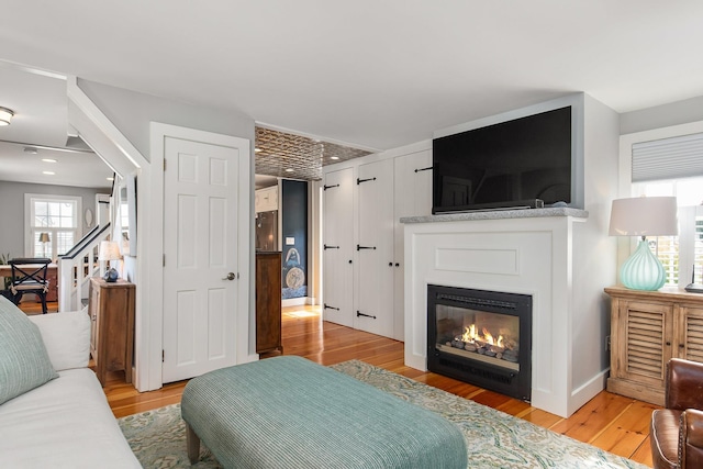 bedroom featuring light wood-style floors and a glass covered fireplace