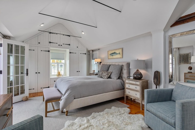 bedroom with lofted ceiling, light wood-style flooring, and two closets