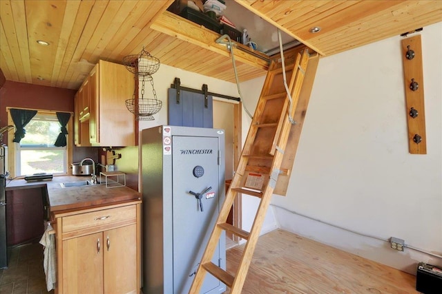 kitchen featuring a barn door, wooden ceiling, wood counters, a sink, and freestanding refrigerator