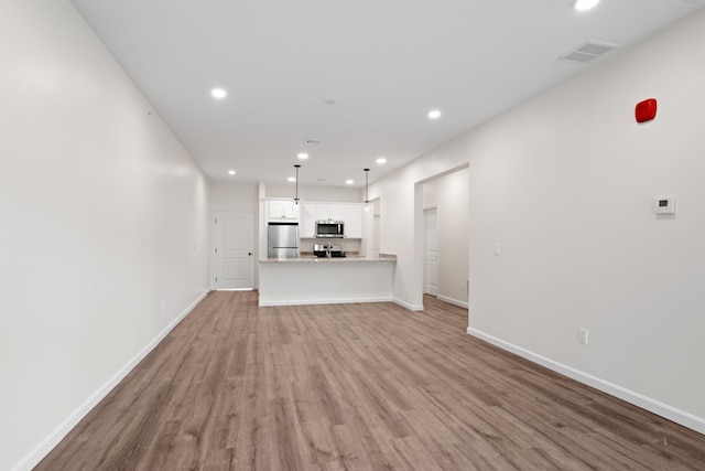 unfurnished living room featuring baseboards, light wood-type flooring, visible vents, and recessed lighting