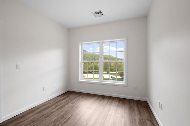 unfurnished room with baseboards, visible vents, and wood finished floors