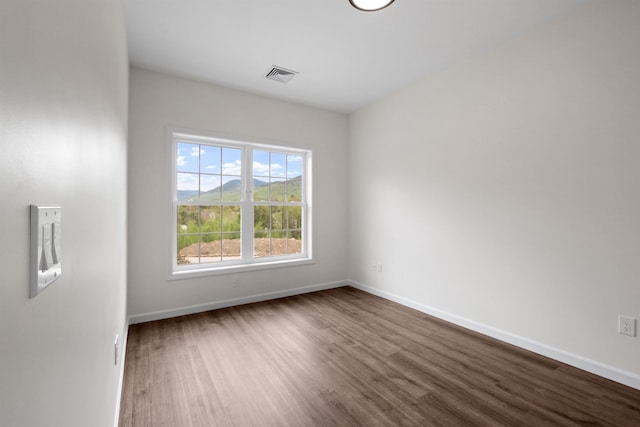 unfurnished room featuring wood finished floors, visible vents, and baseboards