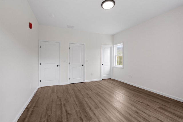 unfurnished bedroom with visible vents, baseboards, and wood finished floors