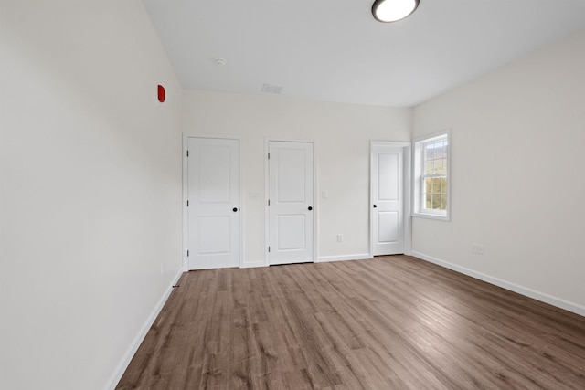 unfurnished bedroom with visible vents, baseboards, and wood finished floors