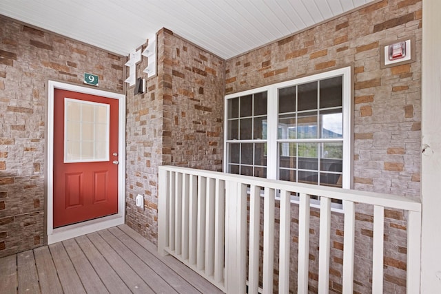 view of exterior entry featuring a porch and brick siding