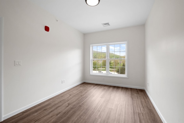 unfurnished room featuring wood finished floors, visible vents, and baseboards