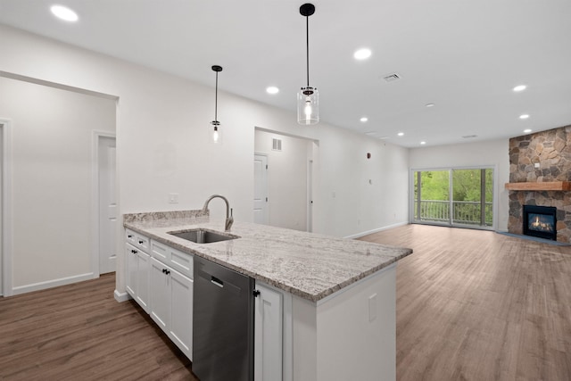 kitchen with white cabinets, wood finished floors, stainless steel dishwasher, a fireplace, and a sink