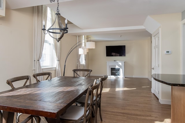 dining area with a notable chandelier, a fireplace, baseboards, and wood finished floors