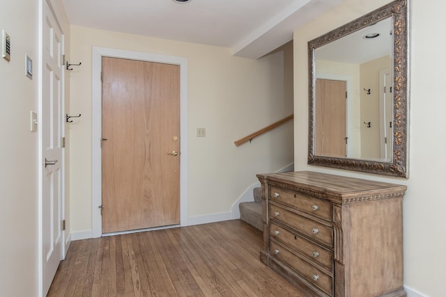 foyer entrance featuring wood-type flooring, stairs, and baseboards