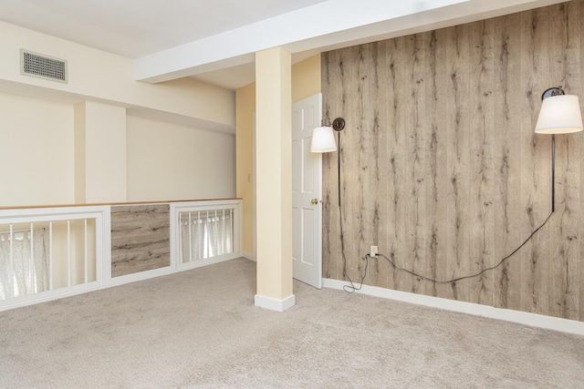 below grade area with wood walls, baseboards, visible vents, and carpet flooring